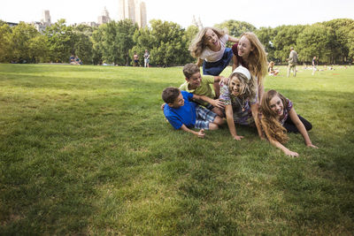 Children enjoying with mother on grassy field at park