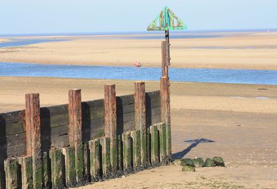 Wooden posts on beach against sky