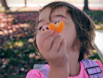 Close-up of girl showing orange heart shape candy