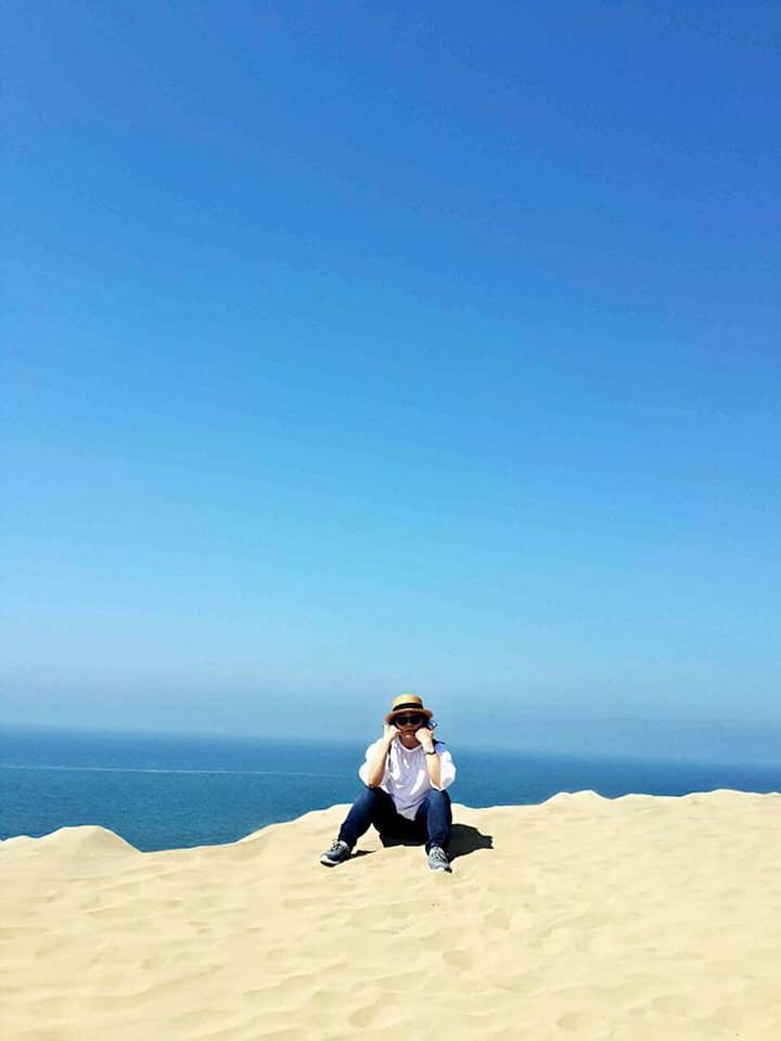 one person, sky, full length, real people, leisure activity, clear sky, beauty in nature, land, day, scenics - nature, lifestyles, nature, sea, copy space, water, sunlight, blue, beach, horizon, horizon over water, outdoors