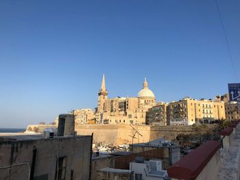 Buildings in city against clear blue sky