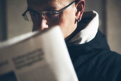 Adult man disturbed reading the newspaper and looking at camera