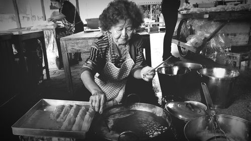 Rear view of woman having food in kitchen