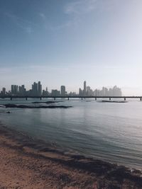 Sea and buildings in city against sky