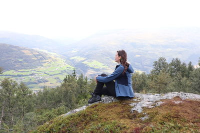 Woman sitting on mountain looking at mountains