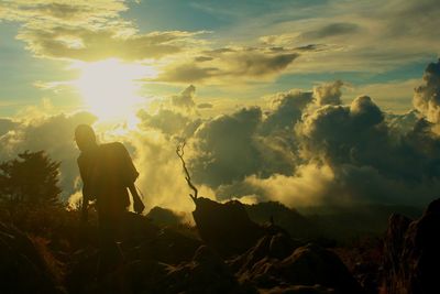 Silhouette rocks on field against sky during sunset