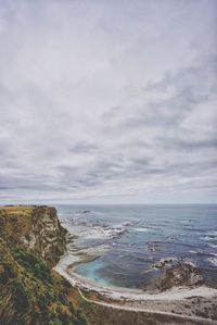 Scenic view of beach against cloudy sky