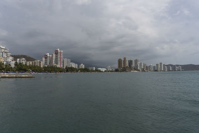 Sea by buildings against sky in city