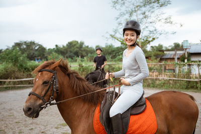 Young woman riding horse on field