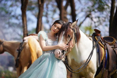 Portrait of a beautiful woman with a horse in the forest background.