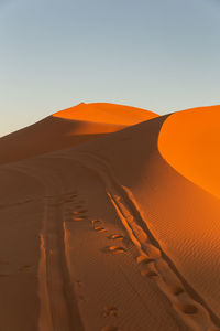 Sand dunes in desert against clear sky