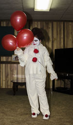 Portrait of girl in costume holding red balloons