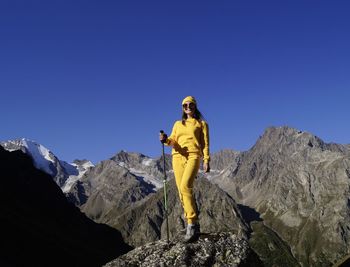 Man standing on rock against clear blue sky