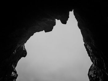 Low angle view of silhouette rock formation against sky