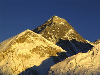 Low angle view of snowcapped mountain against blue sky