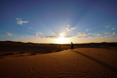 Man on land against sky during sunset