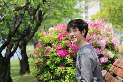 Portrait of smiling teenage boy sitting by flowering plants