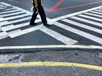 Low section of construction worker holding hardhat while walking on street