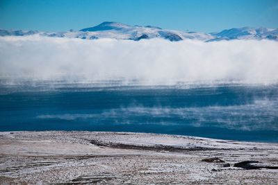 Scenic view of sea and snowcapped mountains against sky