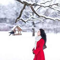 Woman on snow covered tree against sky