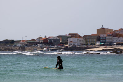 Rear view of woman standing in sea against clear sky