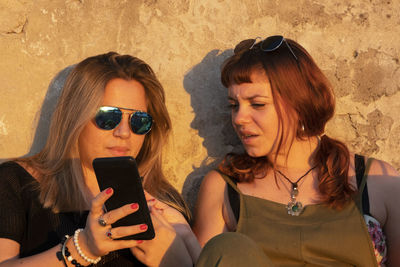 Female teenage friends sharing with smart phone