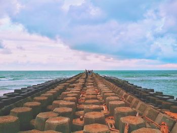 Pier on sea against cloudy sky