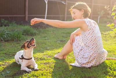 Woman with dog sitting on field