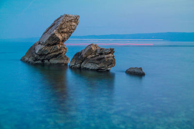 Rock formation in sea against blue sky