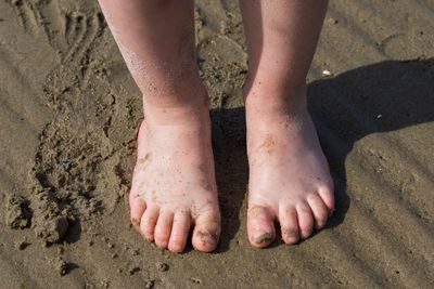 Low section of child standing at beach