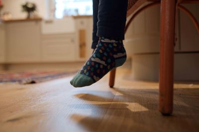 Low section of woman standing on hardwood floor at home