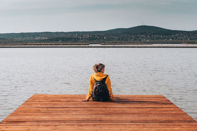 Full length of woman sitting on pier against sky