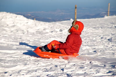 Man wearing red umbrella on snow covered land