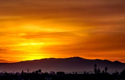 Scenic view of silhouette mountains against orange sky