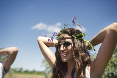 Happy woman wearing tiara while standing against blue sky