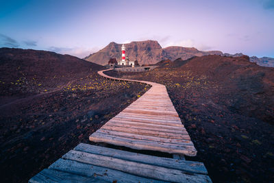 Footpath leading towards mountain during sunset