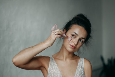 Brunette woman 30 years old doing face massage with a gouache scraper