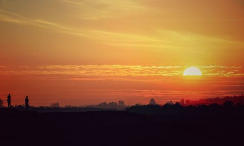 Silhouette landscape against orange sky