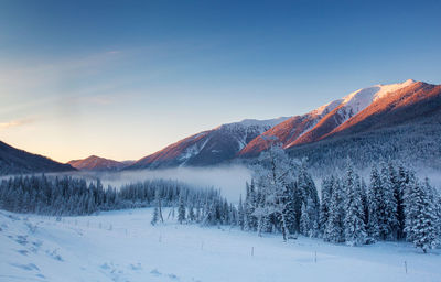 Scenic view of snow covered landscape against sky during sunset