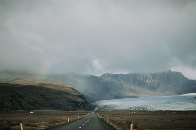 Road by mountains against sky during foggy weather