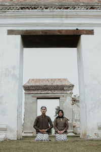 Young man sitting outside building