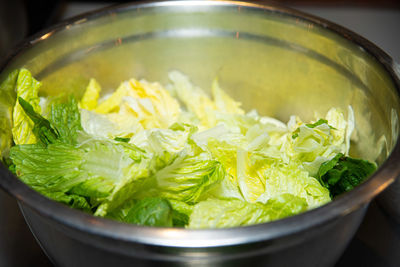 Crisp romaine lettuce leaves in a large stainless steel bowl, prepped for a salad or cooking.