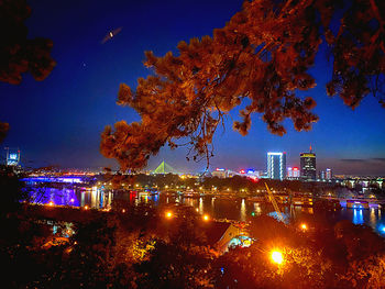 Illuminated buildings against blue sky at night