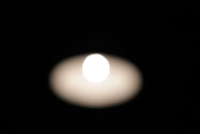 Close-up of illuminated light bulb against black background