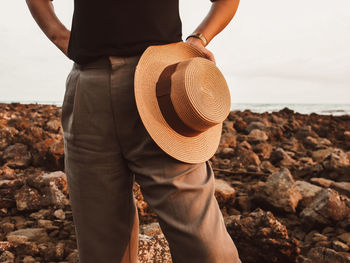 Midsection of man standing on rock by sea