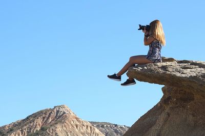 Low angle view of woman against clear blue sky