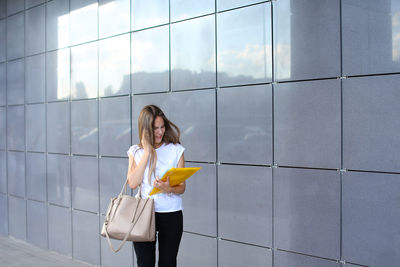 Portrait of young woman standing against wall