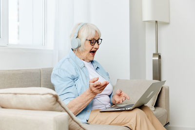 Doctor using laptop while sitting on sofa at home