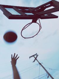 Low section of man playing basketball against sky