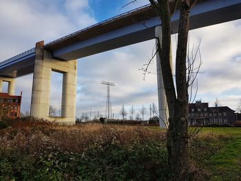 Low angle view of bridge over field against sky